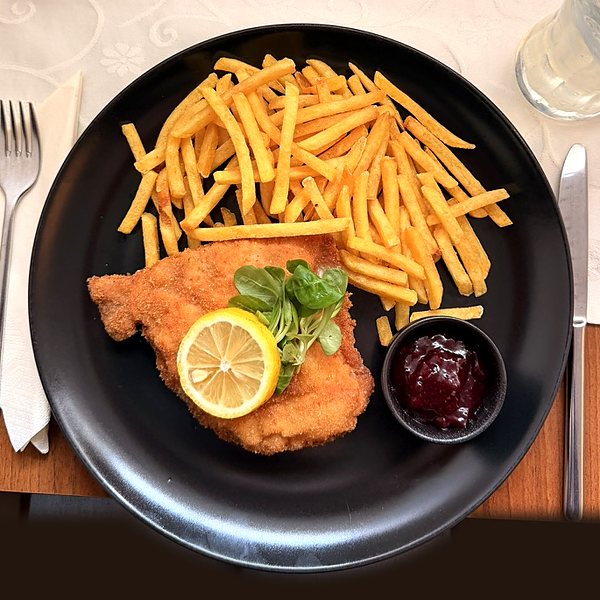 Schweinsschnitzel Wiener Art mit Pommes frites, Zitrone und Preiselbeeren