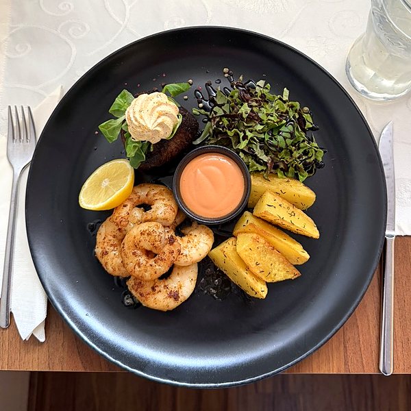 Surf & Turf: Rindsfilet mit Kräuterbutter, gebratene Scampi, Kartoffelspalten, Salat und Cocktailsauce